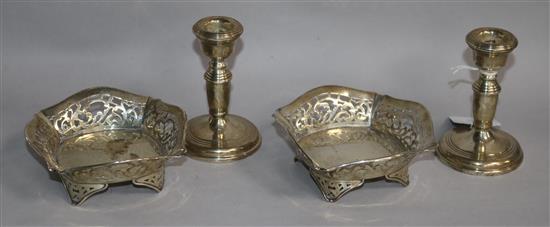 A pair of Edwardian pierced silver dishes and a pair of silver dwarf candlesticks.